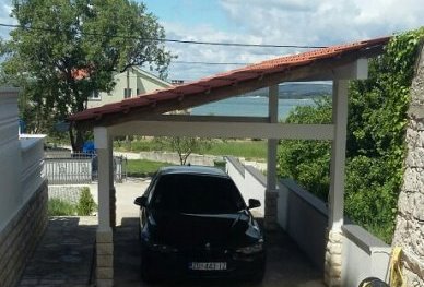 Carport et, à l'arrière-plan, le jardin et une vue sur la mer.
