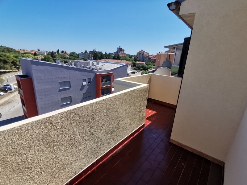 Balcon étroit au sol rouge au-dessus des maisons voisines