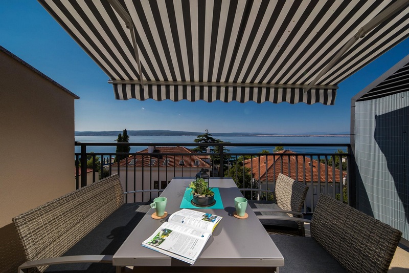 Table de balcon sous un store rayé avec vue sur la mer