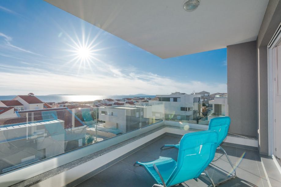 Balcon avec chaises longues turquoise à contre-jour au-dessus du village