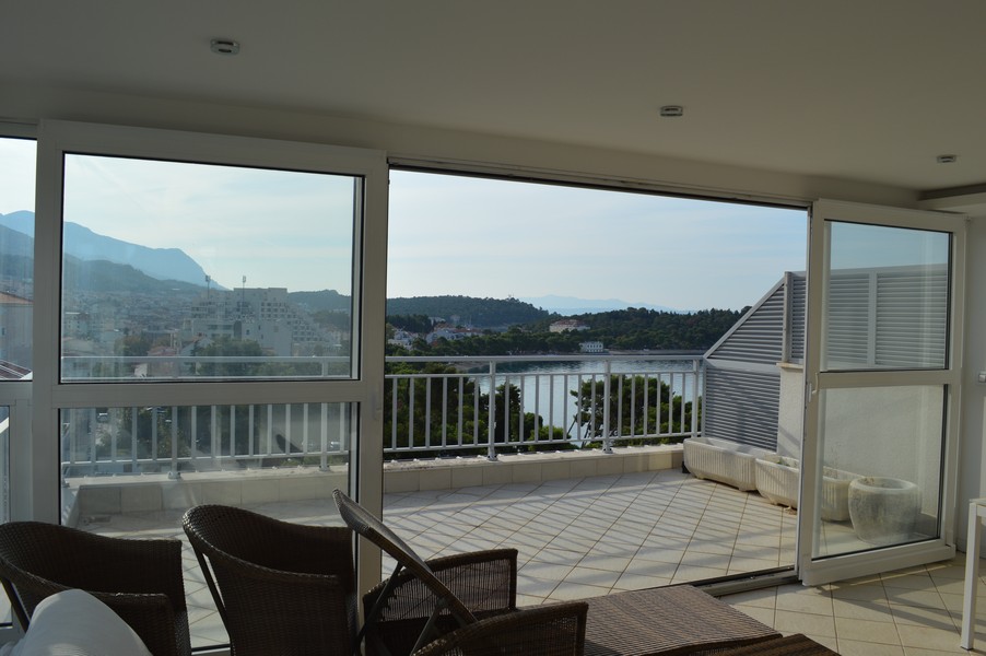 Loggia avec meubles en osier et vue sur les montagnes et la baie