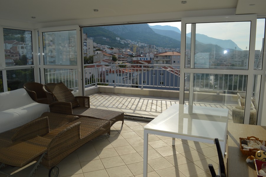 Jardin d'hiver avec bains de soleil en rotin et vue sur le village et les montagnes