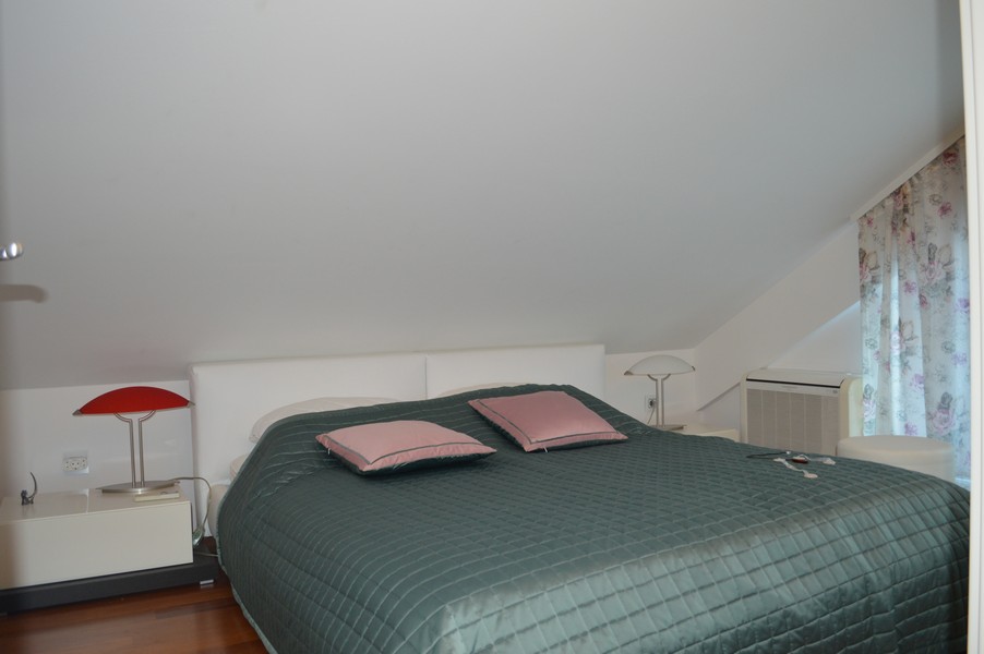 Chambre avec dessus-de-lit vert et lampe de chevet rouge