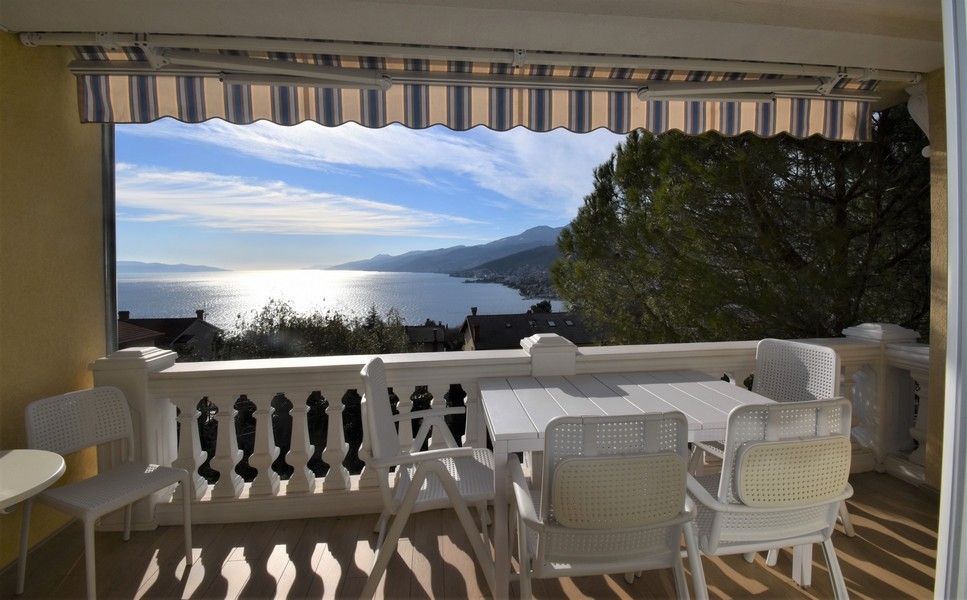 Terrasse couverte avec table et vue mer
