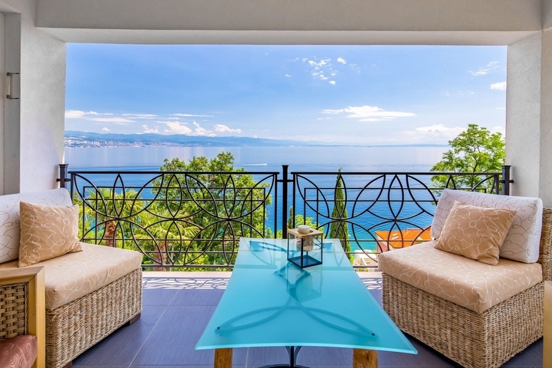 Loggia avec fauteuils et garde-corps en fer forgé au-dessus de la baie
