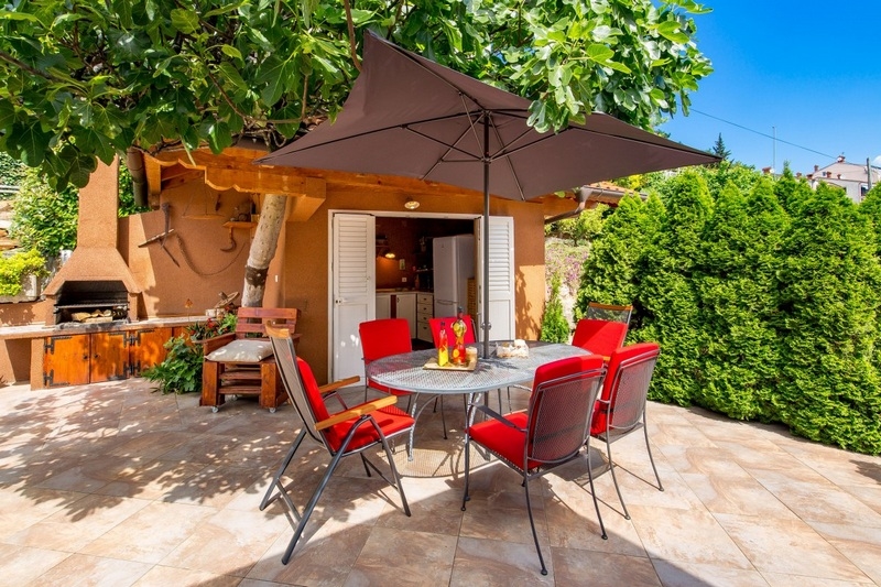 Terrasse avec ensemble de chaises rouges sous le figuier