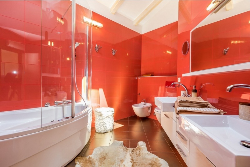 Salle de bains d'un rouge vif avec baignoire d'angle et double vasque
