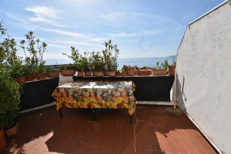 Toit-terrasse avec table et plantes en pot au-dessus de la mer