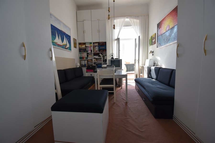 Pièce avec deux canapés foncés et tableaux aux murs