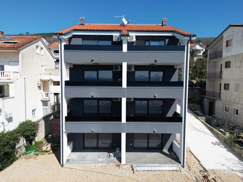Immeuble neuf avec toit de tuiles et balcons sombres vu de l'arrière