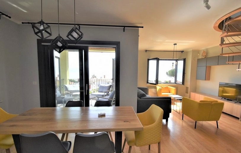 Séjour avec table, fauteuils et porte de terrasse