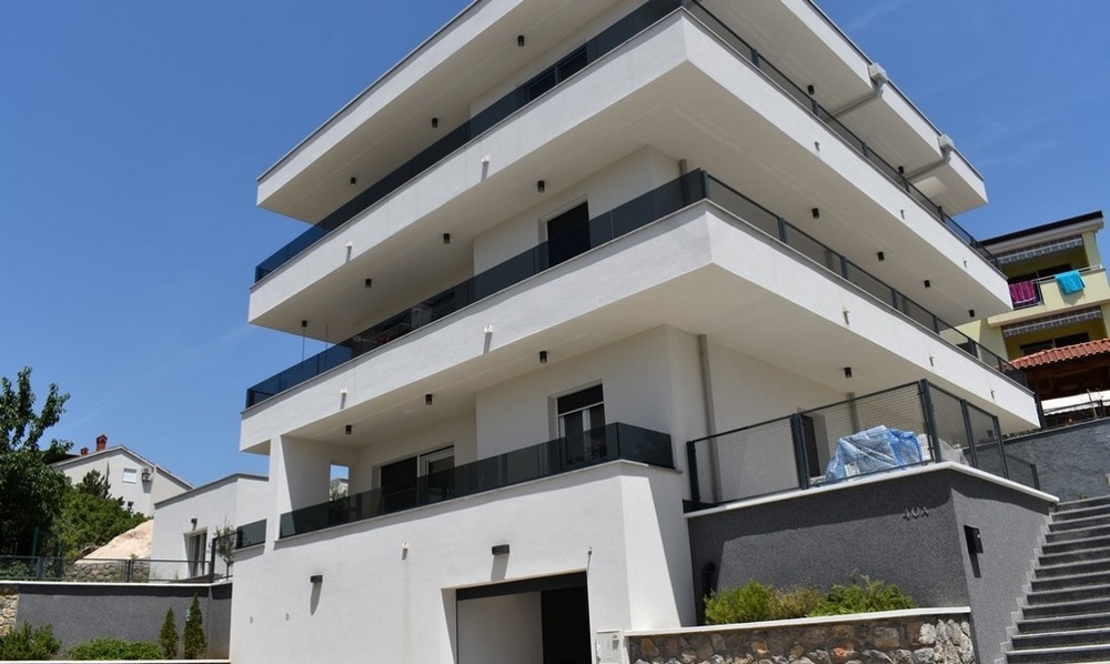 Appartement en rez-de-chaussée dans un immeuble neuf blanc avec larges balcons