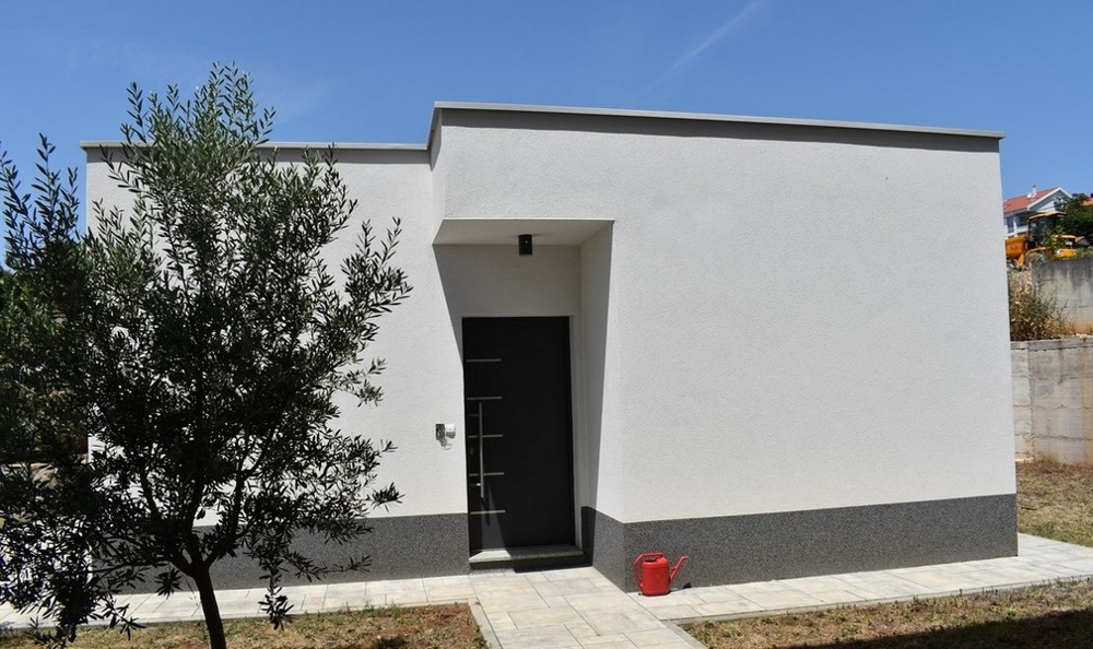 Dépendance basse avec porte d'entrée sombre dans le jardin