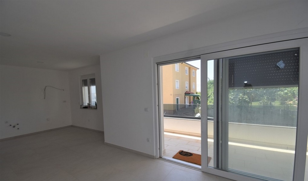 Pièce avec porte coulissante donnant sur la terrasse et maison voisine derrière