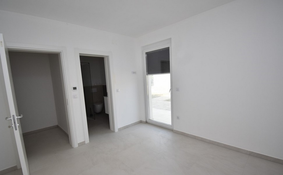 Pièce avec porte de terrasse et passage vers la salle de bains
