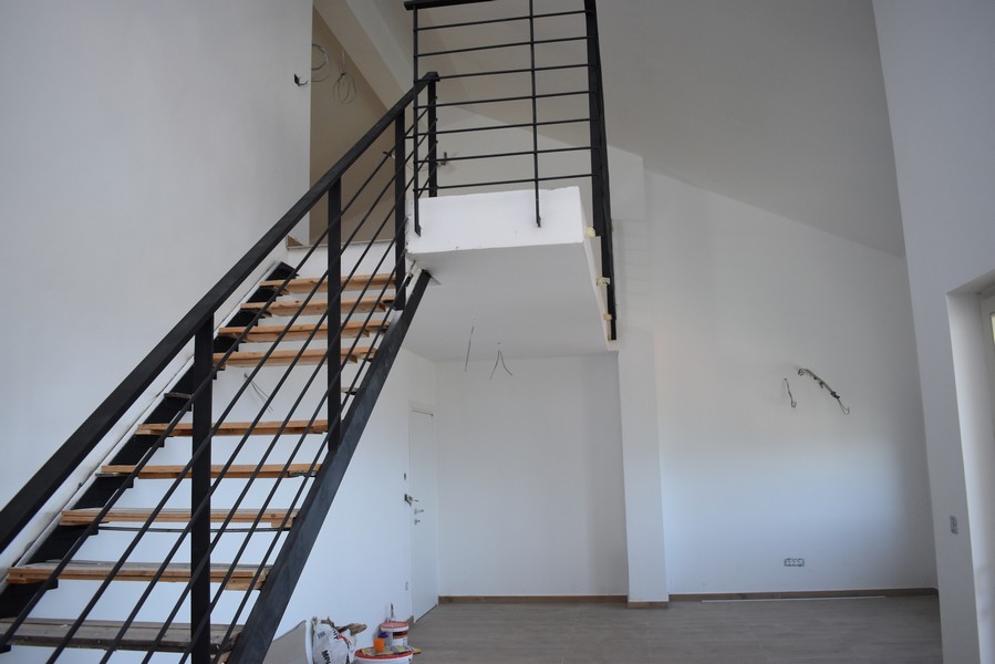 Montée d'escalier vers la galerie devant un mur blanc