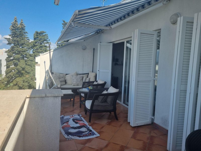 Terrasse avec meubles en rotin devant des portes à lames blanches