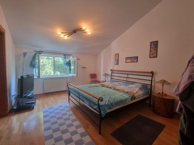 Chambre avec lit en métal et fenêtre donnant sur la verdure