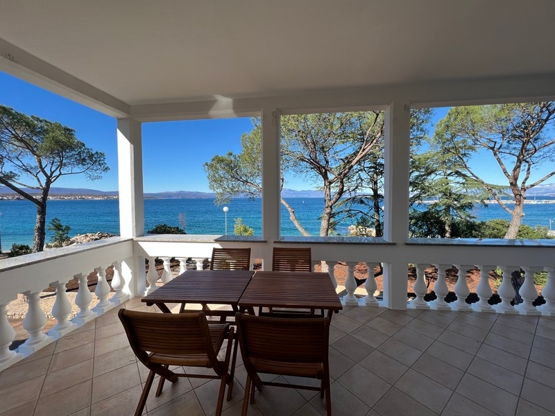 Loggia avec balustrade et table à manger au-dessus de la plage de galets