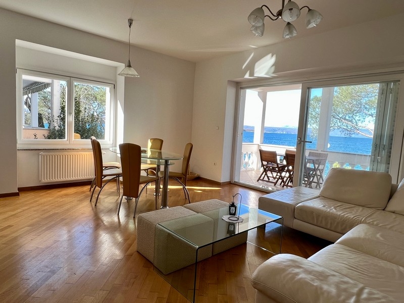 Salon avec coin repas et porte de terrasse donnant sur l'eau