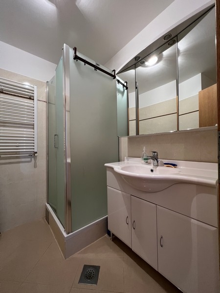 Salle de bains avec douche d'angle et armoire à miroir au-dessus du lavabo