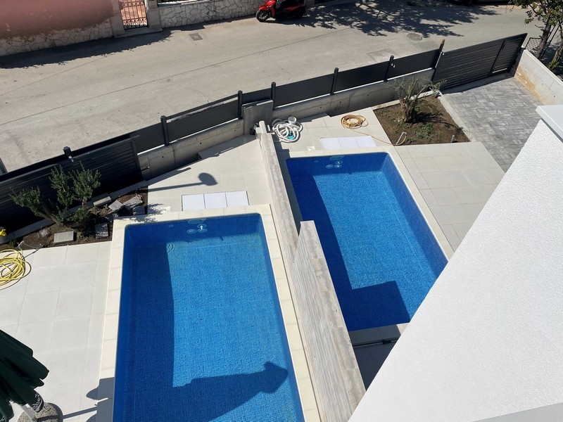 Deux piscines côte à côte vues d'en haut avec un olivier à côté