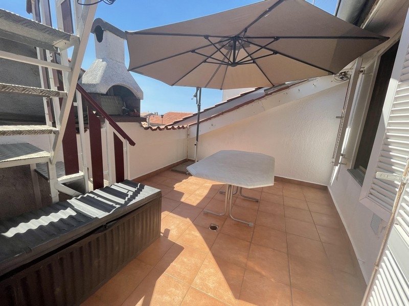 Terrasse avec parasol et escalier extérieur près de la cheminée