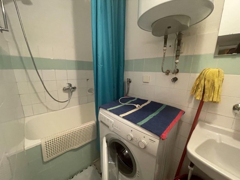 Salle de bains avec baignoire, rideau de douche et lave-linge