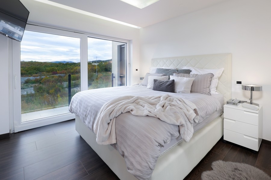 Chambre en blanc avec fenêtre du sol au plafond donnant sur la verdure