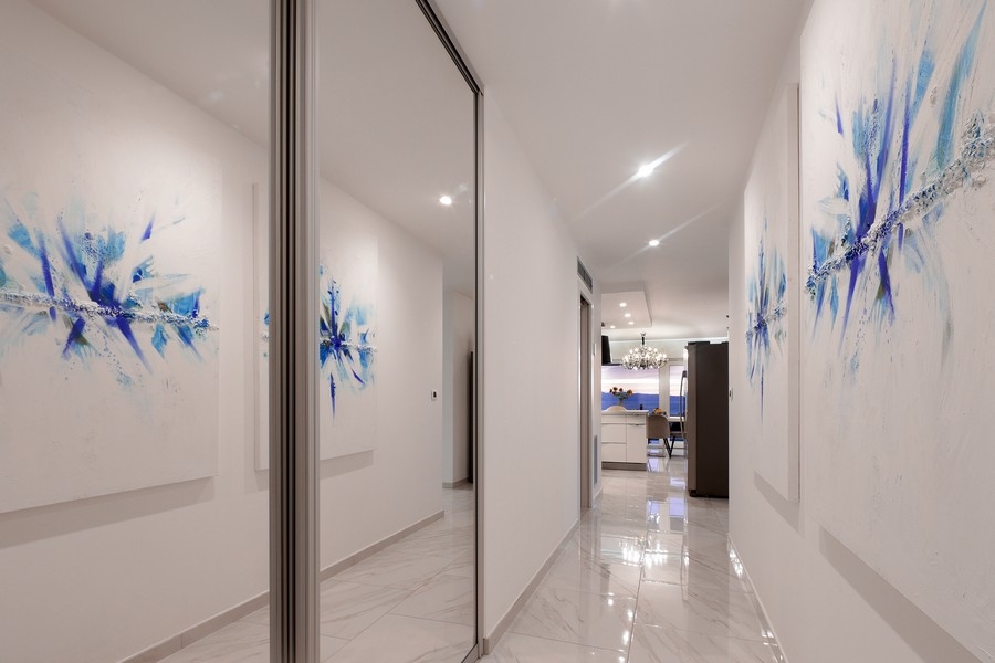 Couloir avec armoire à miroir et tableaux bleus aux murs