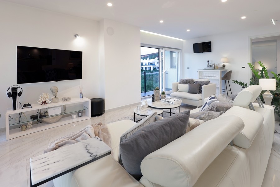 Salon avec mur télévision et accès à la loggia
