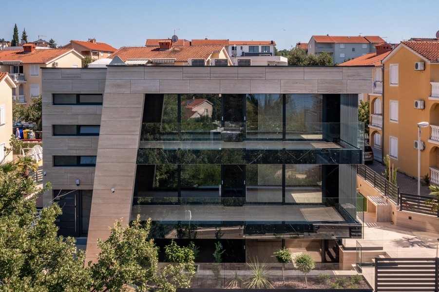 Bâtiment avec façade vitrée et revêtement en pierre naturelle vu de face
