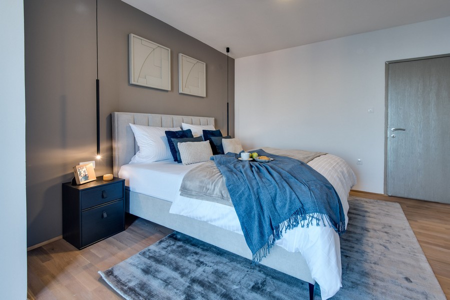 Chambre avec mur gris et couverture bleue sur le lit