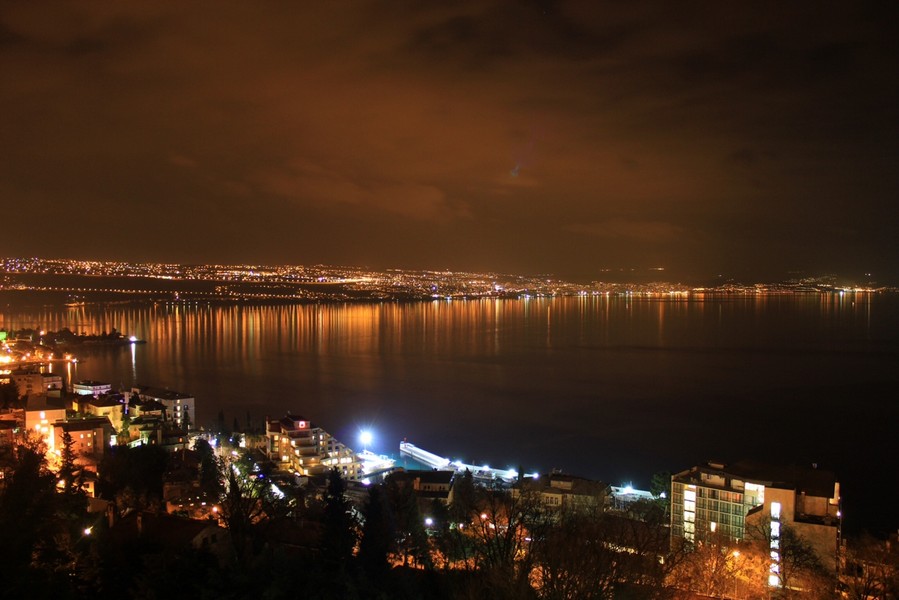 Les lumières de la côte se reflètent la nuit dans l'eau