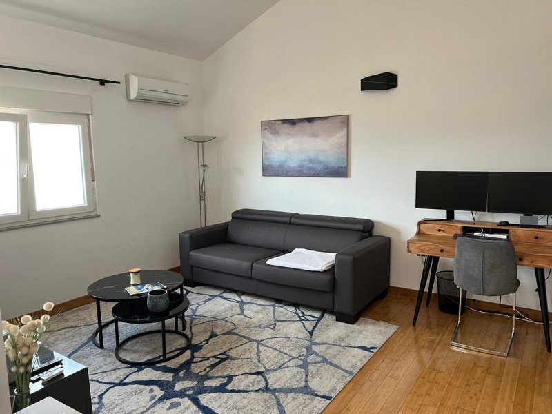 Salon avec canapé sombre et bureau à la fenêtre