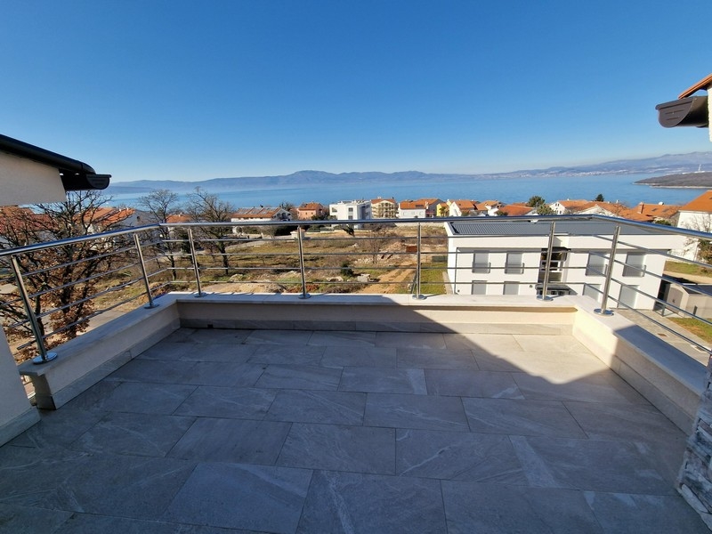 Grande terrasse avec garde-corps en acier et vue sur le village jusqu'à la baie