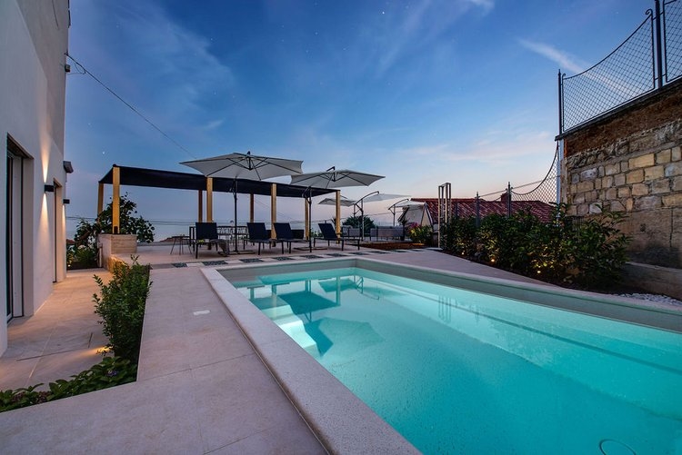 Piscine avec parasols et espace lounge au crépuscule