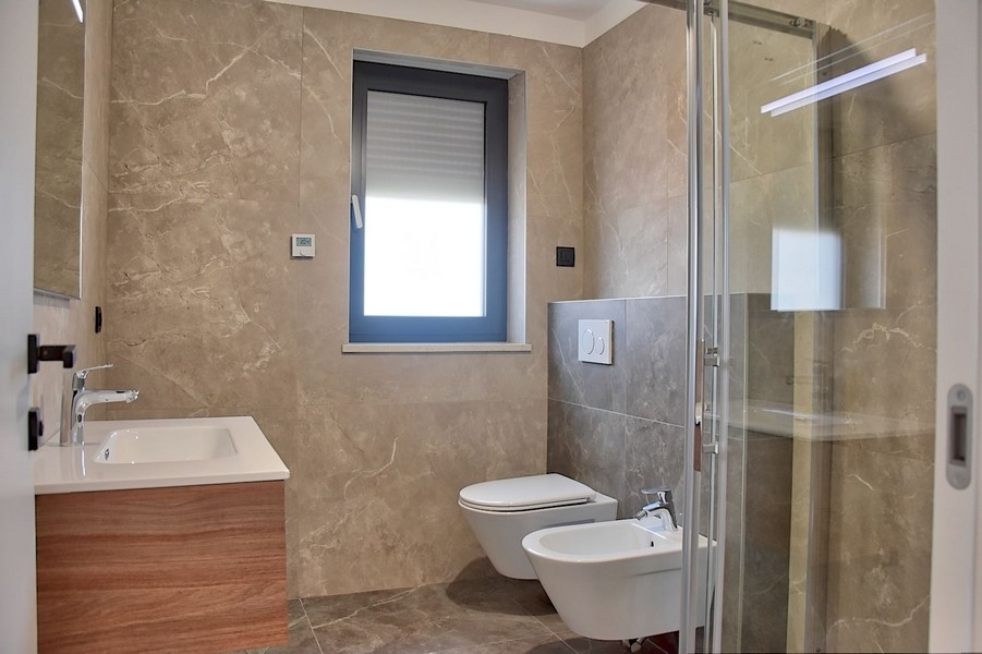 Élégante salle de bains dans un penthouse à vendre en Istrie, avec robinetterie moderne et carrelage en marbre.