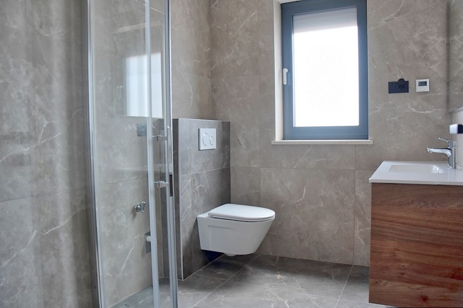Élégante salle de bains dans un penthouse istrien à vendre, avec WC suspendu et meuble-lavabo.