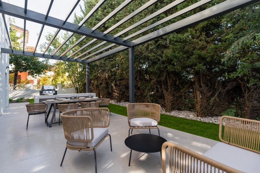 Vue extérieure de la terrasse avec cuisine d'été et coin repas dans un appartement de luxe en Istrie entouré de verdure