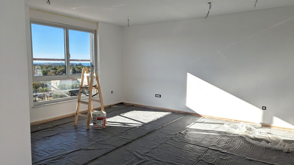 Pièce lumineuse en rénovation avec échelle et matériel de peinture, dans un bien de luxe en Istrie.