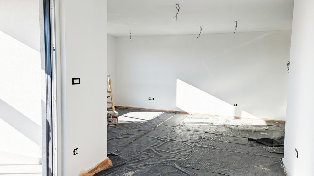 Vaste pièce baignée de soleil avec film de protection au sol, lors de l'achèvement d'un appartement haut de gamme en Istrie