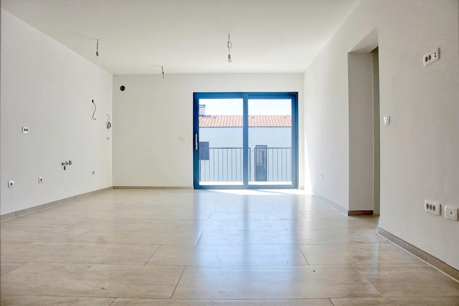 Pièce de vie vide et lumineuse avec grandes portes-fenêtres et sol carrelé, offre immobilière à Porec