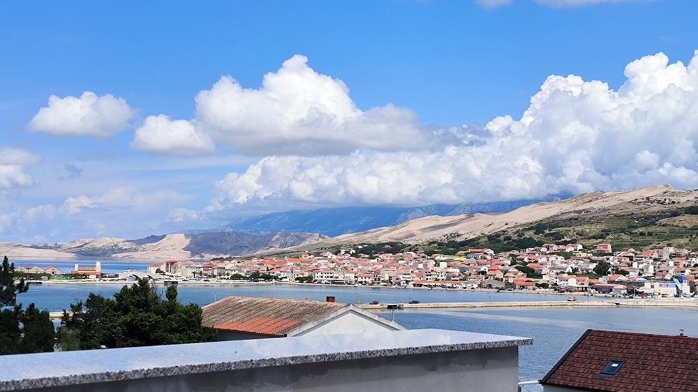 Vue extérieure de l'espace de stationnement d'un appartement à vendre à Pag, Croatie, avec chemin de gravier