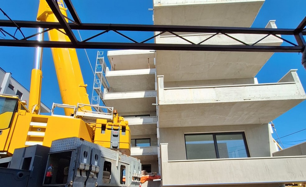 Travaux de grue sur la construction neuve d'un immeuble d'appartements avec balcons