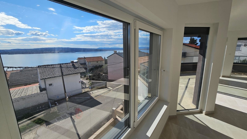 Vue intérieure de l'appartement à vendre à Crikvenica, avec vue sur la mer à travers des baies vitrées jusqu'au sol