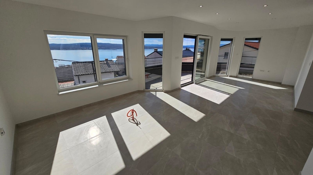 Salon lumineux et vide dans l'appartement à vendre à Crikvenica, golfe du Kvarner, avec grandes fenêtres et vue mer