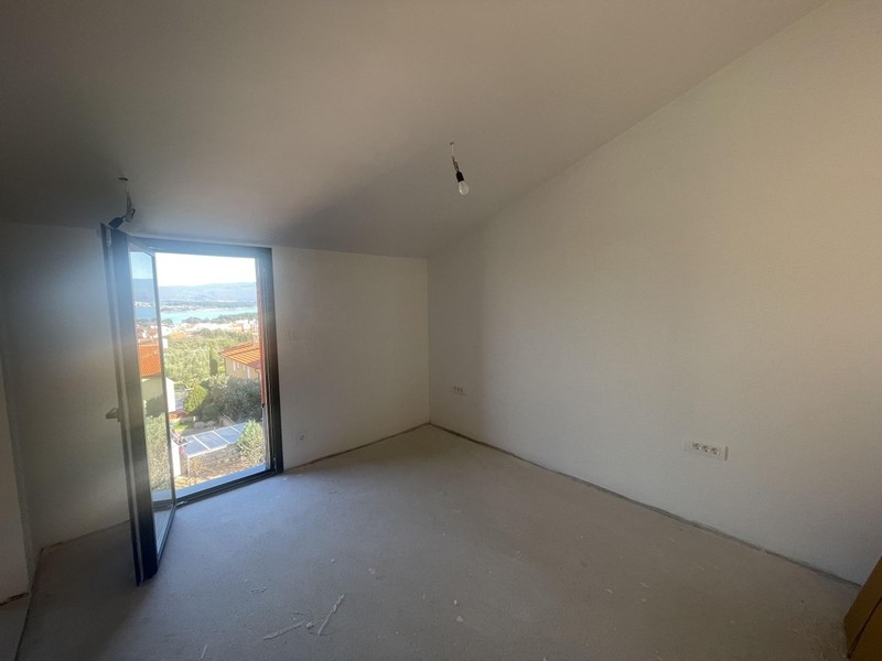Pièce vide avec plafond mansardé et porte-fenêtre jusqu'au sol avec vue mer