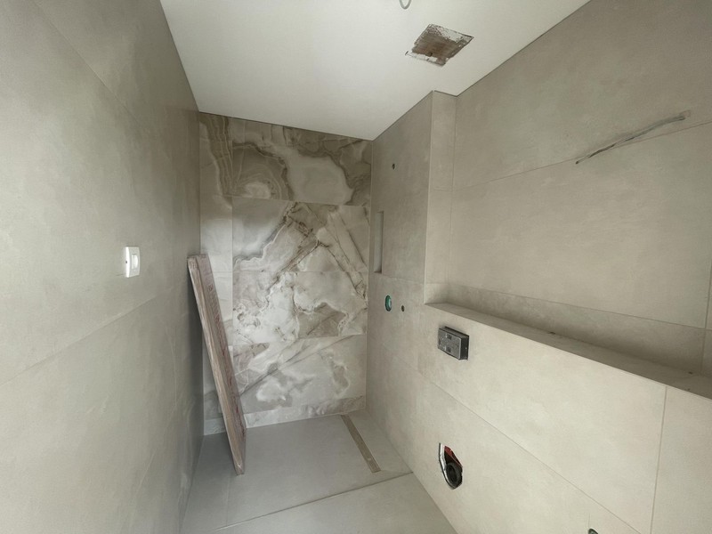 Salle de bains en gros œuvre avec douche carrelée et mur aspect marbre