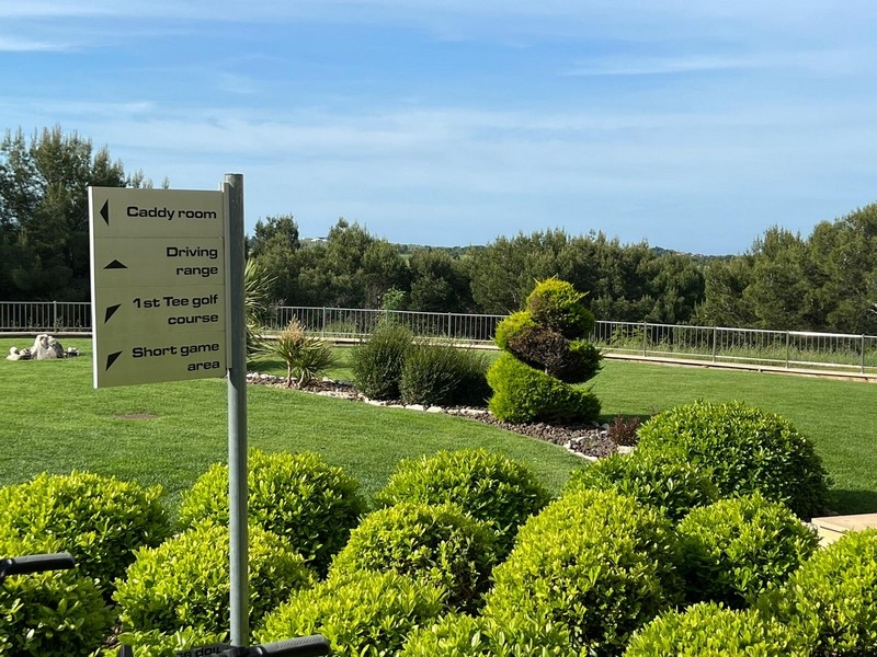 Espace vert entretenu avec panneau indicateur vers le practice et le golf